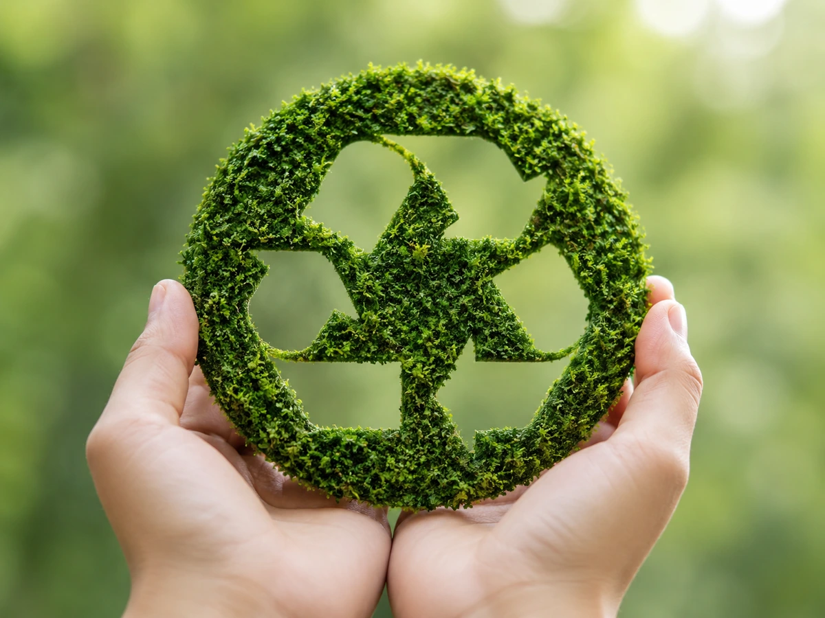 Símbolo natural de reciclaje sostenido entre las manos